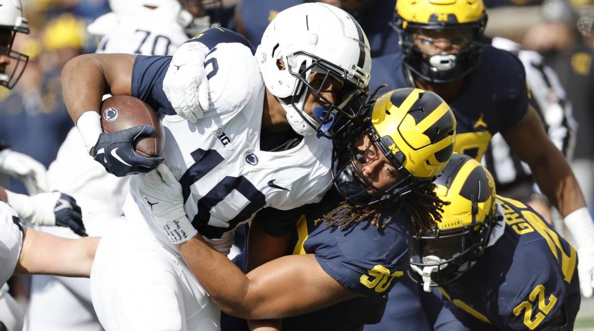 Michigan linebacker Mike Morris tackles Penn State running back Nicholas Singleton in a game.